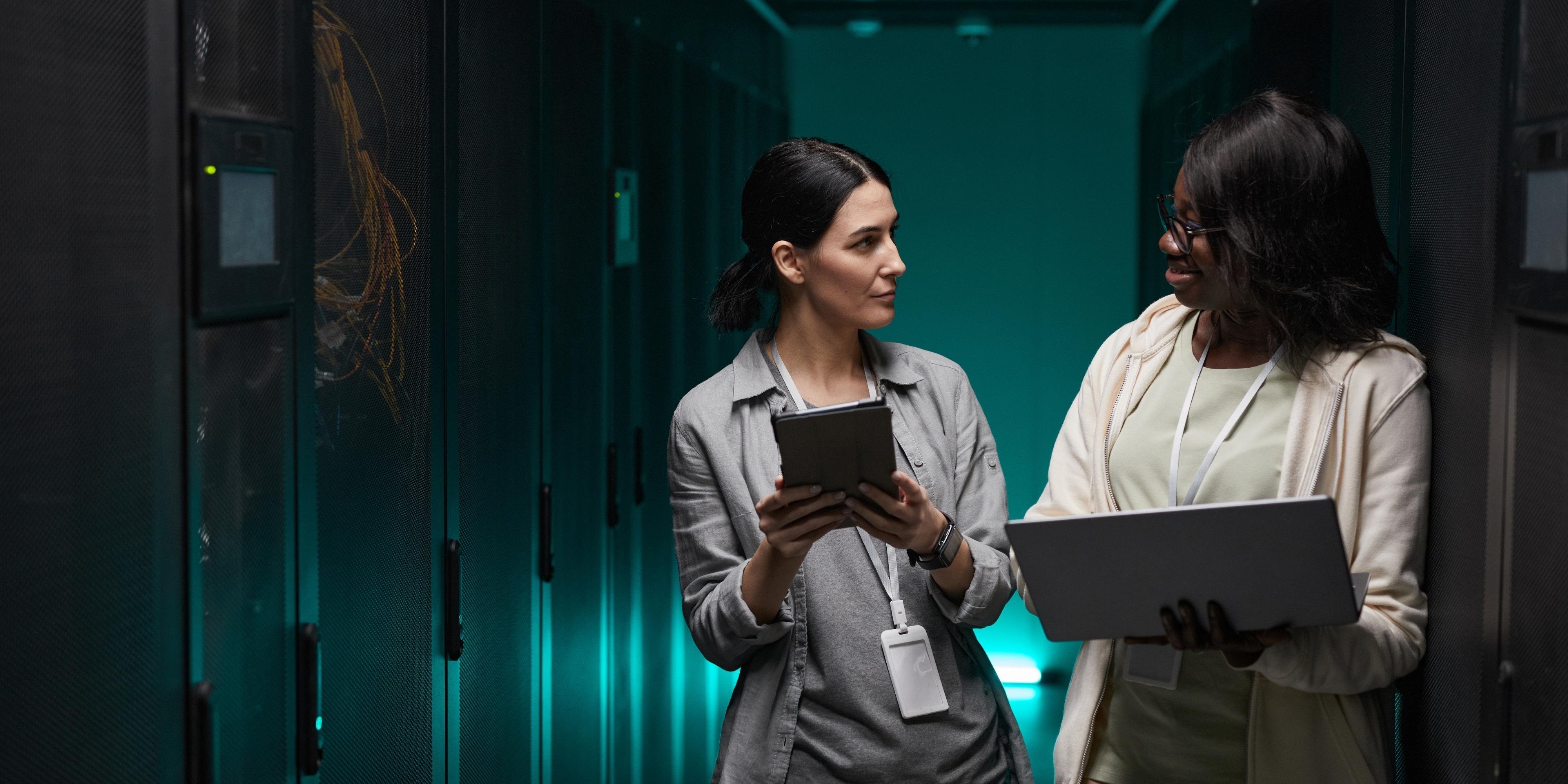 two women it professionals managing assets in a server room